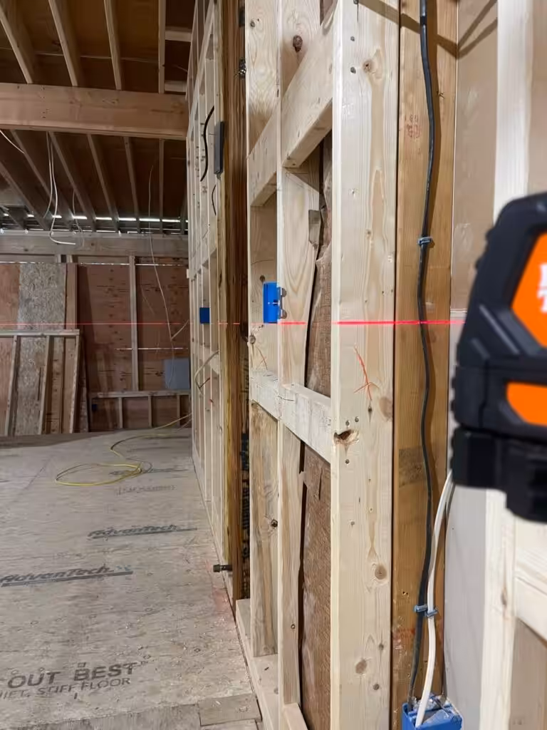 Laser level aligning outlet box height during new-home electrical rough-in.