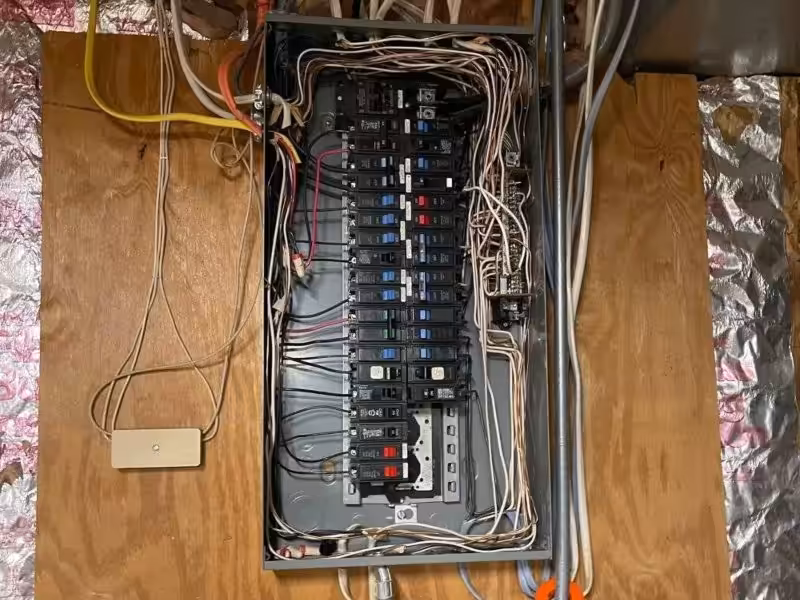 Messy wiring in circuit breaker box identified during home electrical inspection.