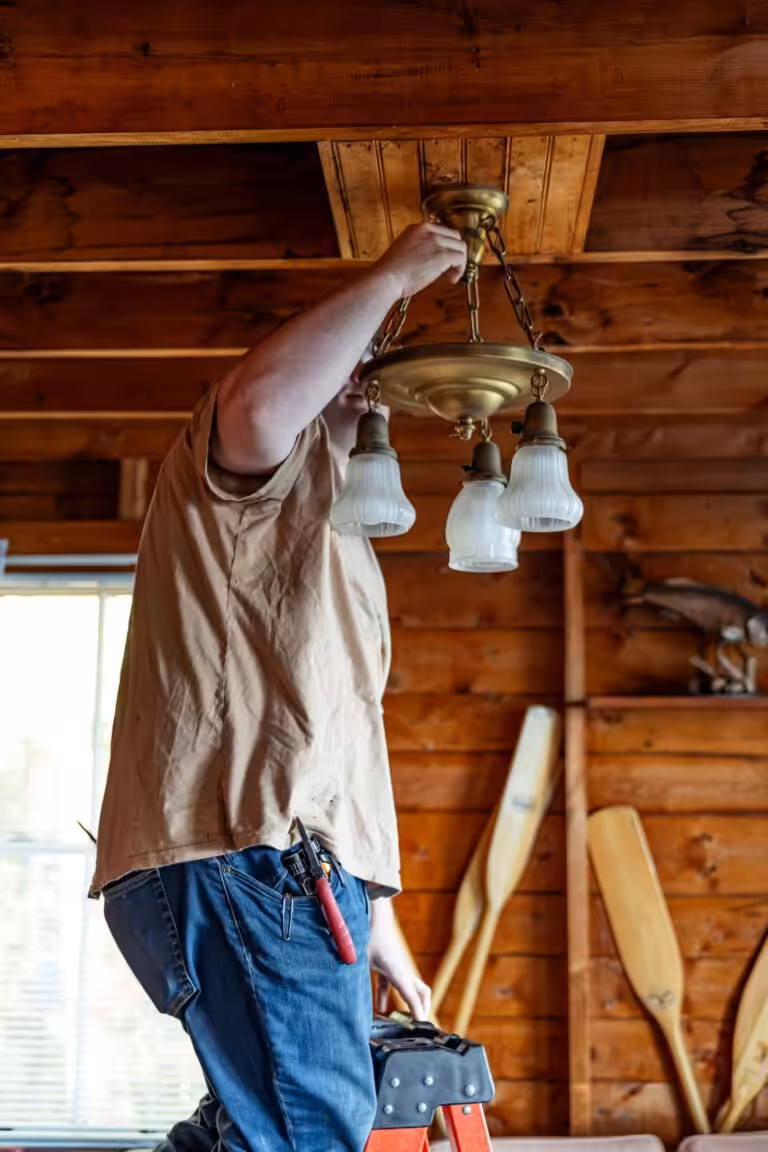 Electrician repairing a ceiling light fixture in a New Hampshire home